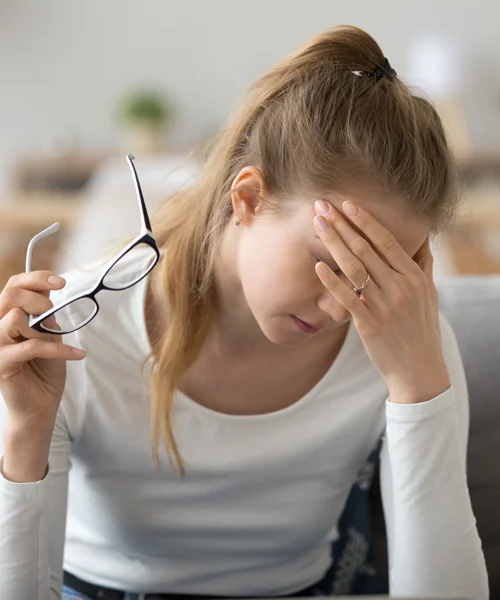 A woman holding her head in pain from eye strain